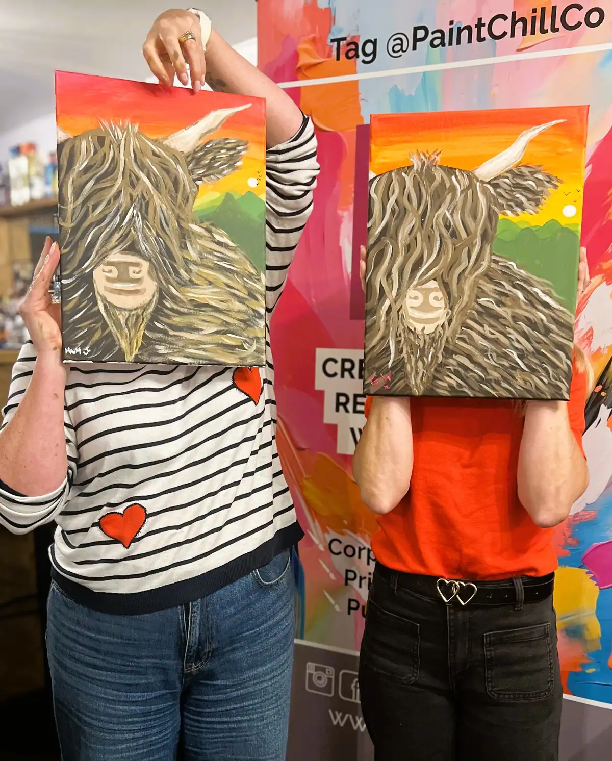 Happy customers holding their Highland cow paintings at a paint & sip event